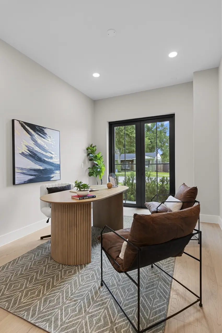 Home office with a wood desk, leather sling chairs, and french doors to the yard
