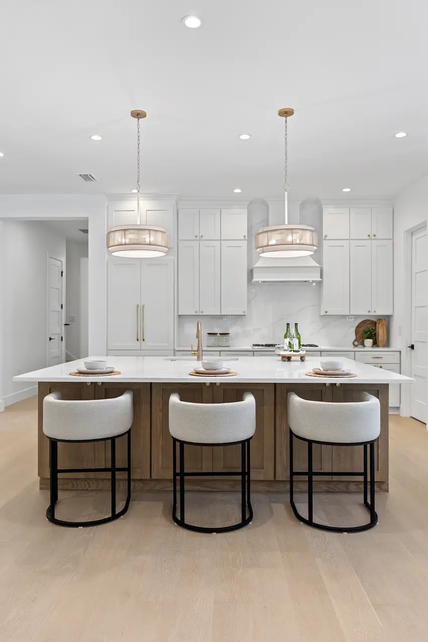 Vertical view of a white kitchen with drum pendants and bar seating
