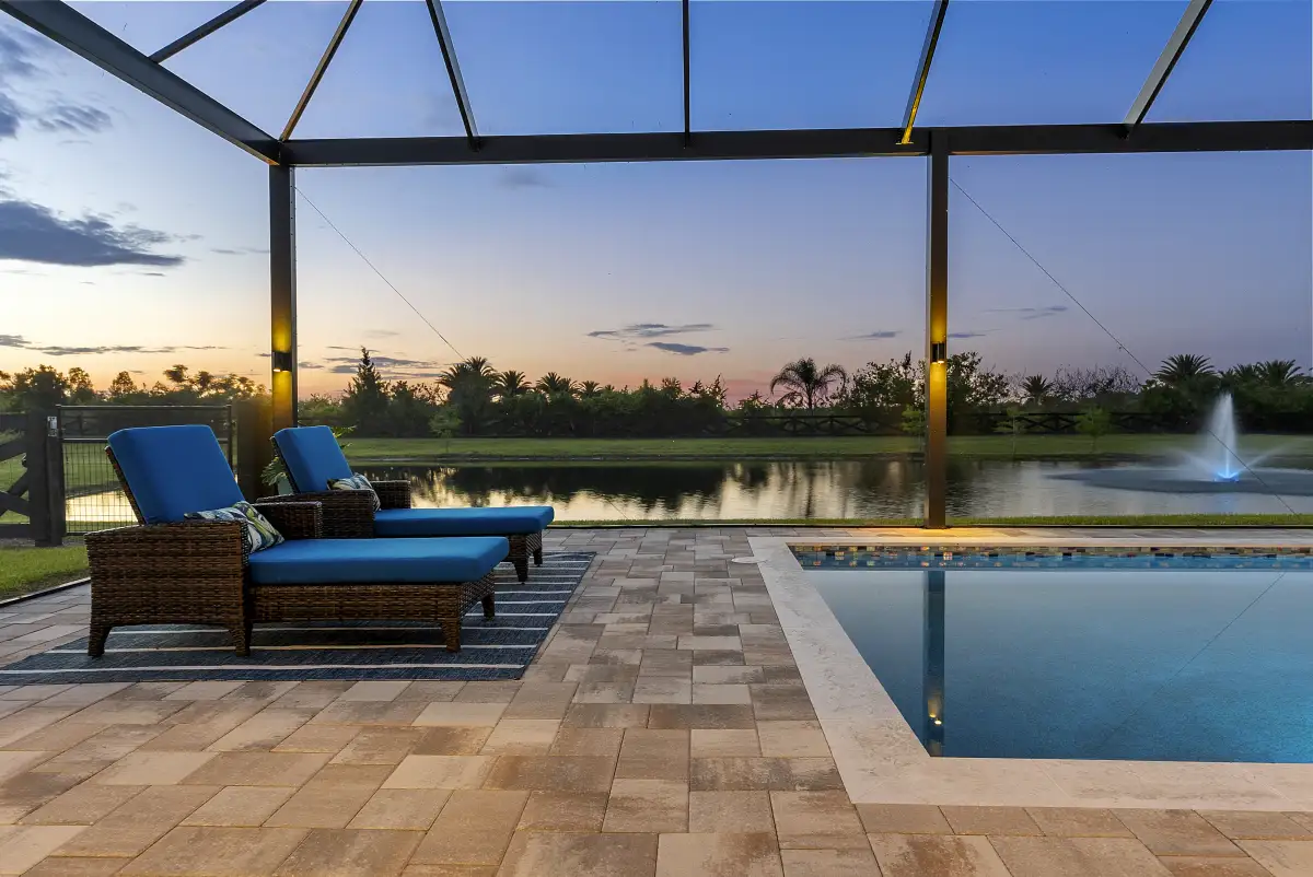 Screened pool and lanai at sunset with lounge chairs and a pond fountain